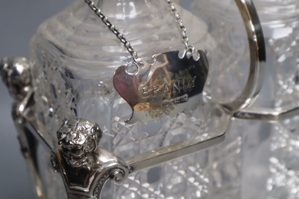 An Edwardian plated decanter stand, fitted three square cut glass decanters and three silver bottle labels, 36cm wide